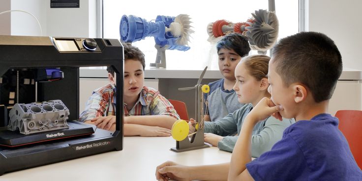 Future Makers students examining 3D-printed parts next to a working 3D printer